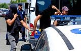 Two of the 12 Israelis suspected of gang raping a British tourist cover their faces with their shirts as they arrive at the Famagusta courthouse in the town of Paralamni, Cyprus, on July 18, 2019. (AP Photo/Petros Karadjias)