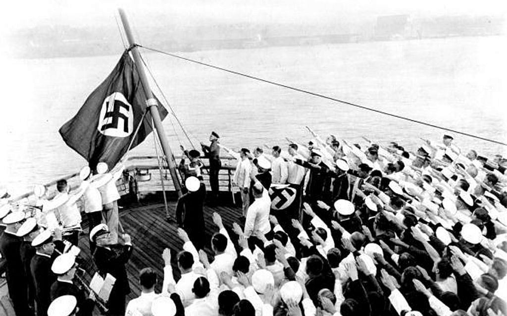 The raising of the new swastika flag aboard the S.S. Bremen as it was docked in the Hudson River. Captain Adolf Ahern, behind the stand with the draped Nazi flag, conducted the ceremonies. (Photo by Jimmy Condon/NY Daily News Archive via Getty Images)