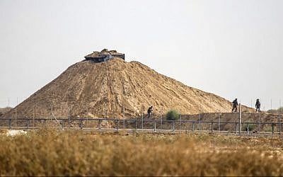 Illustrative: A picture taken from Khan Younis in the southern Gaza Strip shows Israeli soldiers inspecting the area around their observation post next to the border fence with the coastal enclave on August 1, 2019, following a firefight with a Palestinian gunman. (Said Khatib/AFP)