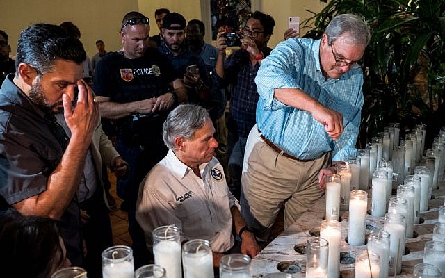 Texas Governor Greg Abbott (C) and El Paso Mayor Dee Margo (R) light candles after a vigil ceremony at Saint Pius X Church, following a deadly mass shooting, in El Paso, Texas, August 3, 2019 (Joel Angel JUAREZ / AFP)