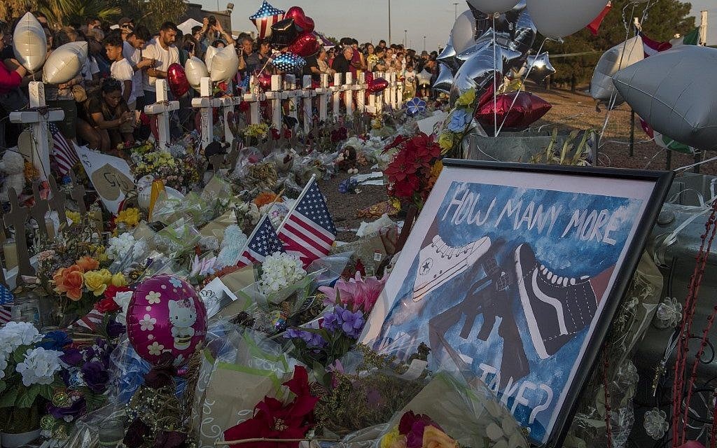People pray and pay their respects at the makeshift memorial for victims of the shooting that left a total of 22 people dead at the Cielo Vista Mall WalMart (background) in El Paso, Texas, on August 6, 2019. (Mark RALSTON / AFP)