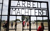 Visitors are seen through an iron gate carrying the German phrase "Arbeit Macht Frei" (work sets you free) at the former concentration camp in Oranienburg, eastern Germany on August 7, 2019. (Odd Andersen/AFP)