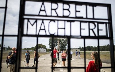 Visitors are seen through an iron gate carrying the German phrase "Arbeit Macht Frei" (work sets you free) at the former concentration camp in Oranienburg, eastern Germany on August 7, 2019. (Odd Andersen/AFP)
