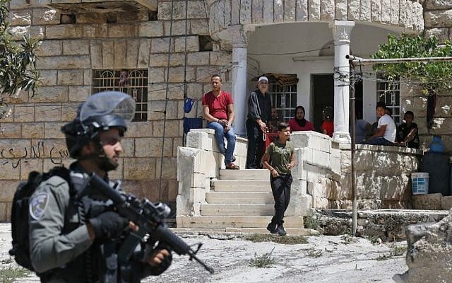 Palestinians look on as Israeli soldiers take part in a house-to-house search operation in the West Bank village of Beit Fajjar near Bethlehem on August 8, 2019, following a stabbing attack. (HAZEM BADER / AFP) Palestinians look on as Israeli soldiers take part in a house-to-house search operation in the West Bank village of Beit Fajjar near Bethlehem on August 8, 2019, following a stabbing attack. (HAZEM BADER / AFP)