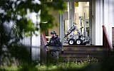 A Norwegian cop walks past a robot in front of the al-Noor Islamic Center mosque, where a gunman armed with multiple weapons went on a shooting spree in the Oslo suburb of Baerum on August 10, 2019. (Terje Pedersen/NTB Scanpix/AFP)