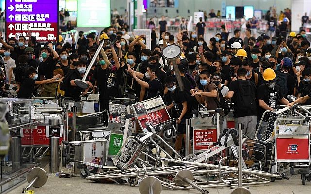 Pro-democracy protestors block the entrance to the airport terminals after a scuffle with police at Hong Kong's international airport late on August 13, 2019. (Manan VATSYAYANA / AFP) Pro-democracy protestors block the entrance to the airport terminals after a scuffle with police at Hong Kong's international airport late on August 13, 2019. (Manan VATSYAYANA / AFP)