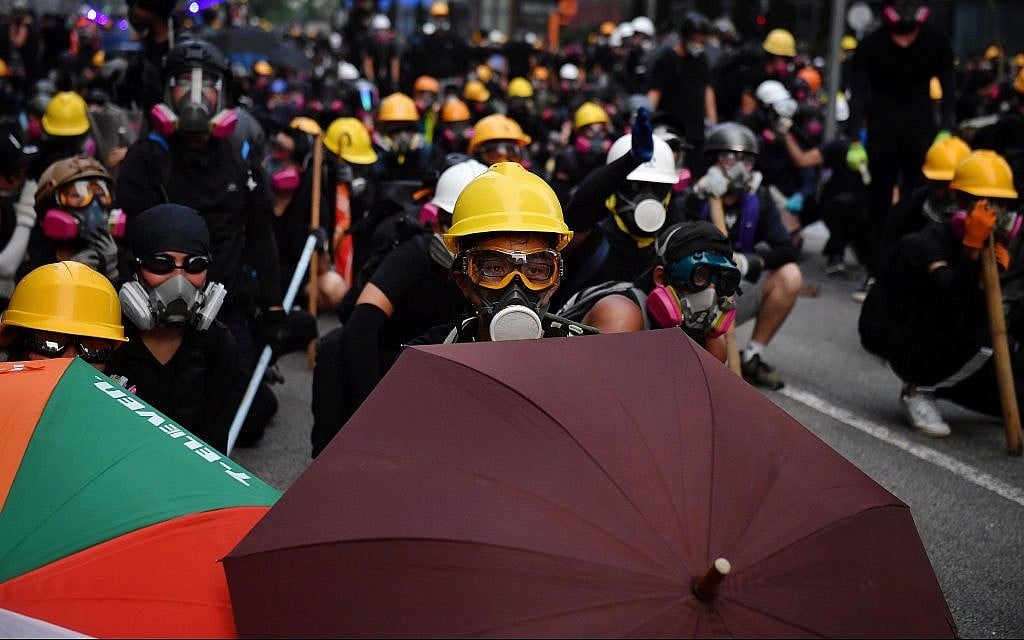 Protesters with umbrellas and protective gear face off with riot police at Kowloon Bay in Hong Kong, August 24, 2019. (Lillian Suwanrumpha/AFP/Getty Images/via JTA) Protesters with umbrellas and protective gear face off with riot police at Kowloon Bay in Hong Kong, August 24, 2019. (Lillian Suwanrumpha/AFP/Getty Images/via JTA)