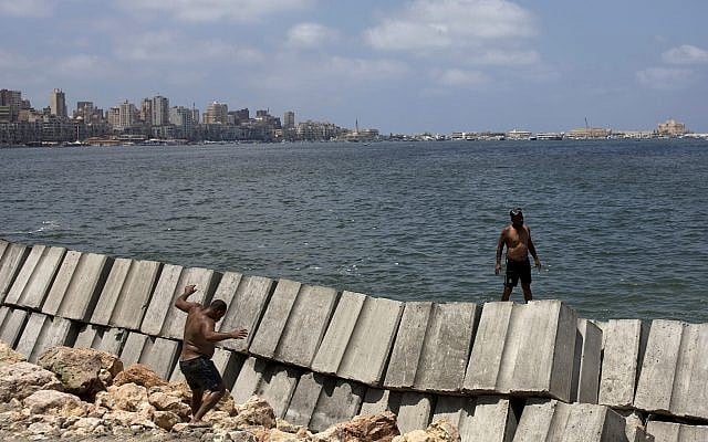 Workers prepare to place cement blocks to reinforce the sea wall against rising water levels on the corniche in Alexandria, Egypt, August 8, 2019. (Maya Alleruzzo/AP)