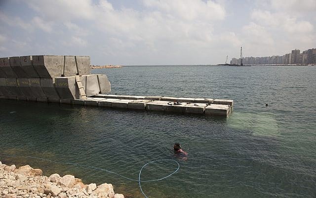 A worker in diving gear prepares to place cement blocks to stave off rising water levels near the corniche in Alexandria, Egypt, August 8, 2019. (Maya Alleruzzo/AP)