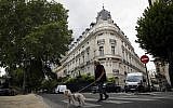 A man walks his dog next to an apartment building owned by Jeffrey Epstein in the 16th district in Paris, August 13, 2019. (AP Photo/Francois Mori)