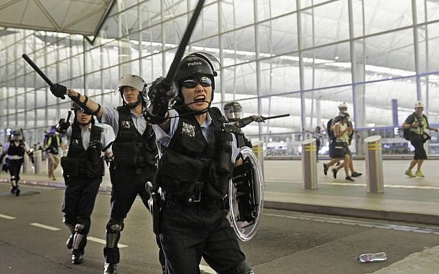 Policemen with batons and shields shout at protesters during a demonstration at the Airport in Hong Kong, Tuesday, Aug. 13, 2019. Riot police clashed with pro-democracy protesters at Hong Kong's airport late Tuesday night, a chaotic end to a second day of demonstrations that caused mass flight cancellations at the Chinese city's busy transport hub. (AP Photo/Vincent Yu) Policemen with batons and shields shout at protesters during a demonstration at the Airport in Hong Kong, Tuesday, Aug. 13, 2019. Riot police clashed with pro-democracy protesters at Hong Kong's airport late Tuesday night, a chaotic end to a second day of demonstrations that caused mass flight cancellations at the Chinese city's busy transport hub. (AP Photo/Vincent Yu)
