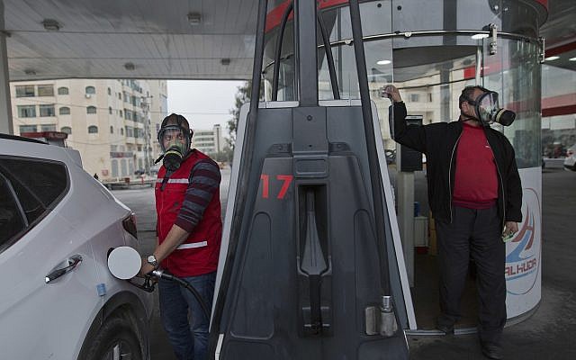 Two Palestinian gas station workers wear teargas masks while supplying vehicles with gasoline during clashes following protests against US President Donald Trump's decision to recognize Jerusalem as the capital of Israel, in the West Bank city of Ramallah, Thursday, Dec. 21, 2017. (AP/Nasser Nasser) Two Palestinian gas station workers wear teargas masks while supplying vehicles with gasoline during clashes following protests against US President Donald Trump's decision to recognize Jerusalem as the capital of Israel, in the West Bank city of Ramallah, Thursday, Dec. 21, 2017. (AP/Nasser Nasser)