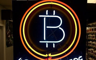 FILE - In this Feb. 7, 2018 file photo, a neon sign hanging in the window of Healthy Harvest Indoor Gardening in Hillsboro, Oregon, shows that the business accepts bitcoin as payment. (AP Photo/Gillian Flaccus, File)