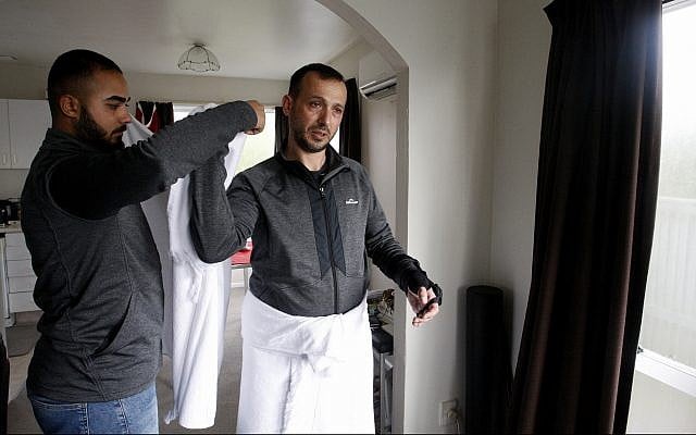 In this July 31, 2019, photo, Temel Atacocugu, who was shot nine times during the Christchurch mosque attacks, tries on the clothes he will wear during the Hajj pilgrimage, in Christchurch, New Zealand. (AP Photo/Nick Perry) In this July 31, 2019, photo, Temel Atacocugu, who was shot nine times during the Christchurch mosque attacks, tries on the clothes he will wear during the Hajj pilgrimage, in Christchurch, New Zealand. (AP Photo/Nick Perry)