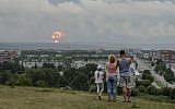 A family watches explosions at a military ammunition depot near the city of Achinsk, Russia on  Aug. 5, 2019. (AP Photo/Dmitry Dub)