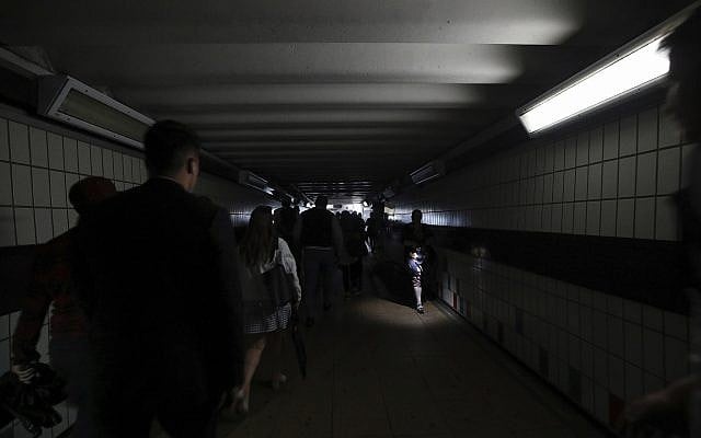 People walk in near darkness at Clapham Junction station during a power cut, in London, Friday, Aug. 9, 2019. (Yui Mok/PA via AP)
