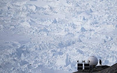 In this Aug. 16, 2019, photo, a woman stands next to an antenna at an NYU base camp at the Helheim glacier in Greenland.  (AP Photo/Felipe Dana)