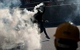 A protester throws a tear gas canister fired by riot police as they face off near the Legislative Council building and the Central Government building in Hong Kong, Monday, August 5, 2019. (AP Photo/Vincent Thian)