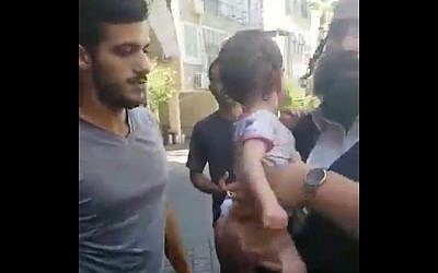 Illustrative: Passersby rescue an infant from a sweltering car in Bnei Brak, August 12, 2019. (Twitter screenshot)