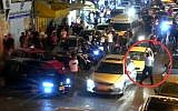 A police officer (marked by red circle) fires in the air to scatter several young men attacking a Jewish driver on Salah Ad-Din Street in East Jerusalem, August 11, 2019. (Israel Police video)