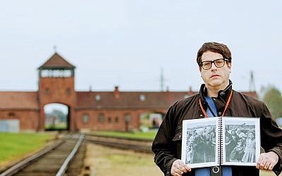 Times of Israel reporter Matt Lebovic at Auschwitz-Birkenau holding a version of 'The Auschwitz Album' image in which his grandmother, Bella (Baila) Solomon, appears, October 2017 (Elan Kawesch/The Times of Israel)