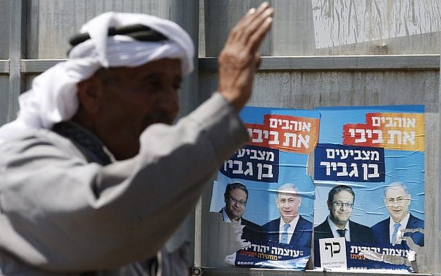 A Palestinian gestures next to campaign posters depicting Prime Minister Benjamin Netanyahu and far-right candidate Itamar Ben Gvir (L) in the West Bank town of Hebron on September 7, 2019. (HAZEM BADER / AFP)