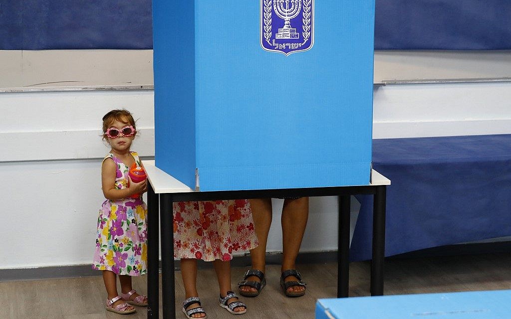 Israeli children accompany their father in a polling booth during Knesset elections at a polling station in Rosh Ha'ayin, on September 17, 2019. (Jack Guez/AFP)