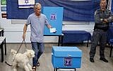 An Israeli man holds his dog while casting his ballot at a polling station in Rosh Haayin, on September 17, 2019. (Jack GUEZ / AFP)