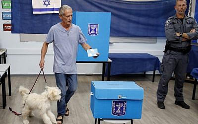 An Israeli man holds his dog while casting his ballot at a polling station in Rosh Haayin, on September 17, 2019. (Jack GUEZ / AFP)