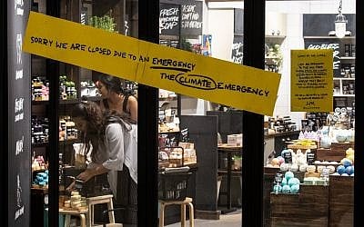 In this picture taken on September 19, 2019, employees arrange a display behind a sign warning customers of a "climate strike" closure of a skin care shop in Singapore on September 20, as part of a global climate change campaign. (Mladen ANTONOV / AFP)