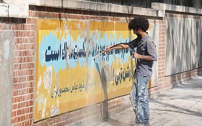 A worker uses a water jet cleaner to erase a mural painting on the wall of the former US embassy in the Iranian capital Tehran on September 29, 2019. (ATTA KENARE / AFP)