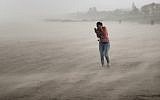 A woman seeks cover from wind, blowing sand and rain whipped up by Hurricane Dorian as she walks on the beach on September 2, 2019 in Cocoa Beach, Florida. (Scott Olson/Getty Images/AFP)