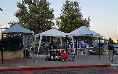 Activists set up stands for various political parties outside a polling station in Modiin, September 17, 2019. (Raoul Wootliff/Times of Israel)