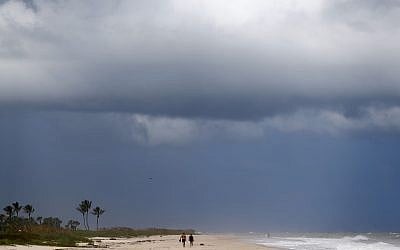 People walk on a largely deserted beach of the Atlantic Ocean on the barrier island in Vero Beach, Fla., Sunday, Sept. 1, 2019. The barrier island is under a voluntary evacuation today and a mandatory evacuation tomorrow in preparation for the possibility of Hurricane Dorian making landfall. (AP Photo/Gerald Herbert)