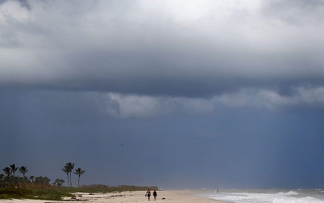 People walk on a largely deserted beach of the Atlantic Ocean on the barrier island in Vero Beach, Fla., Sunday, Sept. 1, 2019. The barrier island is under a voluntary evacuation today and a mandatory evacuation tomorrow in preparation for the possibility of Hurricane Dorian making landfall. (AP Photo/Gerald Herbert) People walk on a largely deserted beach of the Atlantic Ocean on the barrier island in Vero Beach, Fla., Sunday, Sept. 1, 2019. The barrier island is under a voluntary evacuation today and a mandatory evacuation tomorrow in preparation for the possibility of Hurricane Dorian making landfall. (AP Photo/Gerald Herbert)