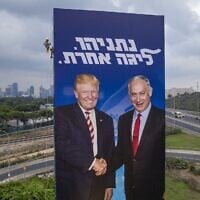 A worker hangs an election campaign billboard of the Likud party that shows Prime Minister Benjamin Netanyahu, right, shaking hands with US President Donald Trump, in Tel Aviv, September 8, 2019. The slogan reads: 'Netanyahu -- a league of his own.' (AP/Oded Balilty)