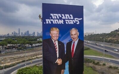 A worker hangs an election campaign billboard of the Likud party that shows Prime Minister Benjamin Netanyahu, right, shaking hands with US President Donald Trump, in Tel Aviv, September 8, 2019. The slogan reads: 'Netanyahu -- a league of his own.' (AP/Oded Balilty)