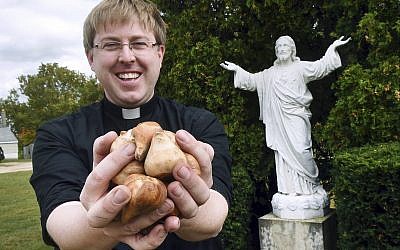 In this  Sept. 24, 2019 photo, The Rev. Andrew K. Nelson, pastor of Saint Ignatius of Loyola Parish in Somersworth, New Hampshire and Saint Mary Parish in Rollinsford, New Hampshire holds tulip bulbs which will be planted at the church on High Street in Somersworth (Deb Cram/Foster's Daily Democrat via AP)