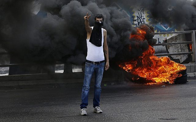 An anti-government protester makes victory sign next to tires that were set on fire to block a road during a demonstration, in Beirut, Lebanon, Sunday, Sept. 29, 2019. (AP Photo/Bilal Hussein) An anti-government protester makes victory sign next to tires that were set on fire to block a road during a demonstration, in Beirut, Lebanon, Sunday, Sept. 29, 2019. (AP Photo/Bilal Hussein)