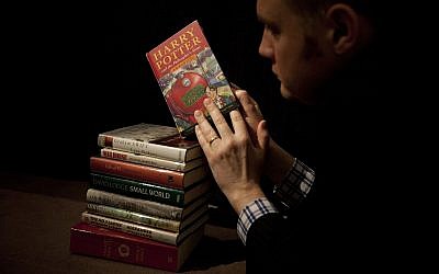 In this Monday, May 20, 2013 file photo, Sotheby's director of the department of printed books and manuscripts Dr Philip Errington poses for photographers by holding a first edition copy of the first Harry Potter book "Harry Potter and the Philosopher's Stone" containing annotations and illustrations by author J.K. Rowling on top of a stack of other annotated first edition books featuring at auction, at the auction house's premises in London. Wizarding legend Harry Potter's tale has turned 20. Author JK Rowling's first novel, Harry Potter and the Philosopher's Stone, was published in Britain on June 26, 1997. Since then, it has sold more than 450 million copies worldwide and has been translated into 79 languages. (AP Photo/Matt Dunham, File)