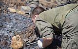 An Israeli soldier examines the remains of a rocket near the village of Avivim on the Israel-Lebanon border, Monday, Sept. 2, 2019. (AP Photo/Ariel Schalit)