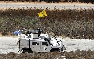 Spanish UN peacekeepers patrolling along the Lebanese-Israeli border pass a Hezbollah flag, in the southern Lebanese village of Kfar Kila, Lebanon, September 2, 2019. (AP Photo/Hussein Malla)