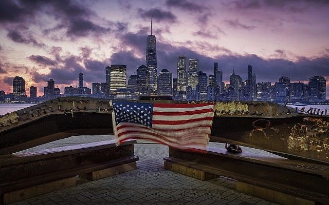 A US flag hanging from a steel girder, damaged in the September 11, 2001, attacks on the World Trade Center, blows in the breeze at a memorial in Jersey City, New Jersey, September 11, 2019, as the sun rises behind One World Trade Center building and the re-developed area where the Twin Towers of World Trade Center once stood in New York City on the 18th anniversary of the attacks. (AP Photo/J. David Ake) A US flag hanging from a steel girder, damaged in the September 11, 2001, attacks on the World Trade Center, blows in the breeze at a memorial in Jersey City, New Jersey, September 11, 2019, as the sun rises behind One World Trade Center building and the re-developed area where the Twin Towers of World Trade Center once stood in New York City on the 18th anniversary of the attacks. (AP Photo/J. David Ake)