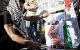 Palestinians burn pictures depicting Israeli Prime Minister Benjamin Netanyahu during a protest against the PM's visit to the West Bank city of Hebron, September 4, 2019 (Wisam Hashlamoun/Flash90)