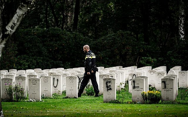 A police officer walks past graves which have been vandalized with graffiti in the British World War II Commonwealth Graves cemetery in Mierlo, east of Eindhoven, Netherlands, September 13, 2019. (Rob Engelaar/ANP/AFP) A police officer walks past graves which have been vandalized with graffiti in the British World War II Commonwealth Graves cemetery in Mierlo, east of Eindhoven, Netherlands, September 13, 2019. (Rob Engelaar/ANP/AFP)