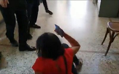 Screen capture from video showing Kan public broadcaster reporter Vered Pelman, bottom, after having been allegedly shoved to the floor by family members of one of two Israeli rape suspects in Greece, September 3, 2019. (Twitter)