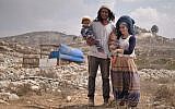 Neria Zarog (c) with his wife and child in front of their home in the Kumi Ori outpost, a neighborhood of the Yitzhar settlement in the northern West Bank. The IDF has issued an order barring him from the West Bank. (Avraham Shapira)