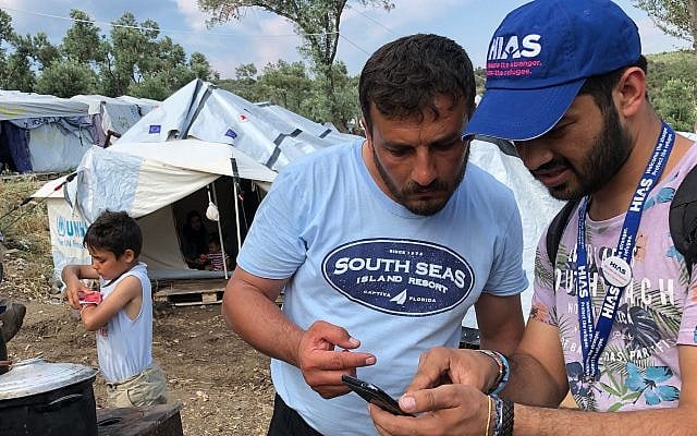 HIAS Greece translator Jalal Barezkai (R) works with a Syrian refugee in an encampment just outside the Moria refugee camp on the Greek island of Lesvos, May 9, 2018. Barezkai is a former refugee from Afghanistan. (Bill Swersey/HIAS via JTA) HIAS Greece translator Jalal Barezkai (R) works with a Syrian refugee in an encampment just outside the Moria refugee camp on the Greek island of Lesvos, May 9, 2018. Barezkai is a former refugee from Afghanistan. (Bill Swersey/HIAS via JTA)