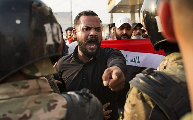 An Iraqi protester gestures in front of security forces during a demonstration against state corruption, failing public services and unemployment, on October 2, 2019 in the southern city of Basra (Hussein FALEH / AFP)