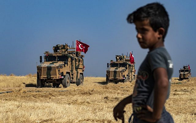 A Syrian boy watches as Turkish military vehicles, part of a US military convoy, take part in a joint patrol in the Syrian village of al-Hashisha on the outskirts of Tal Abyad along the border with Turkey, on October 4, 2019. (Delil Souleiman/AFP)